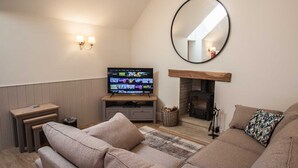 Ein gemütliches Wohnzimmer mit Kamin, Fernseher und einer bequemen Couch.