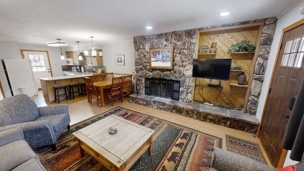 Ein Wohnzimmer mit Kamin aus Stein, einem Fernseher und einem Essbereich mit Stühlen und Tisch.