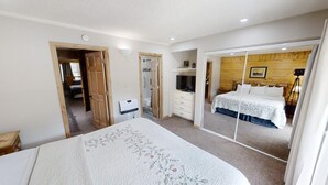 Ein Schlafzimmer mit Bett, Fernseher, Spiegel und einer Holzwand.