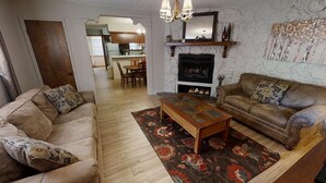 Ein Wohnzimmer mit zwei Sofas, einem Holztisch und einem Kamin.