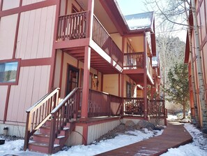 A multi-story building with balconies, a wooden staircase, and a snow-covered ground.