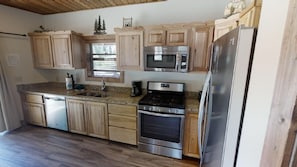 Enjoy cooking in this well-equipped kitchen with a stainless steel refrigerator, microwave, double oven, and ample storage space.