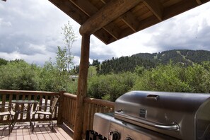 A wooden deck with a grill and chairs overlooking a forested hillside. - Paradise Found on the River - In Town - New Property - Pet Friendly (Red River)