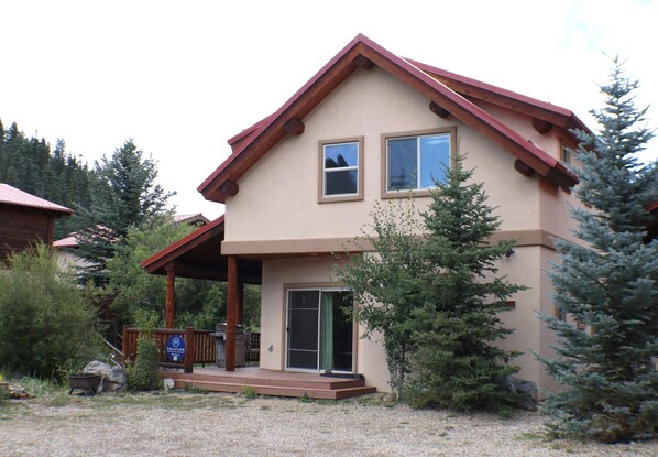A two-story house with a porch, a sliding glass door, and a sign indicating a vacation rental. - Paradise Found on the River - In Town - New Property - Pet Friendly (Red River)