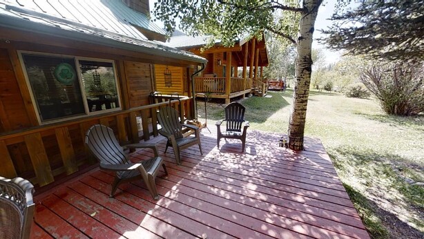 Una cabaña de madera con un porche, dos sillas Adirondack y una terraza.