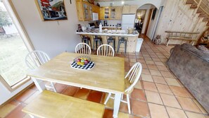 Enjoy a casual dining experience in this inviting space with a wooden table and comfortable seating area.