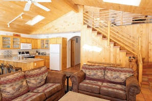 A cozy wooden interior with a kitchen, a sofa, and a staircase.