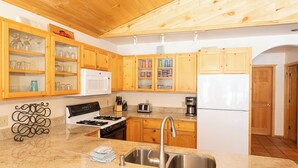 A kitchen with wooden cabinets, a stainless steel sink, a stove, a microwave, and a refrigerator. - Ski View Chalet - In Town - New Property - Pet Friendly (Red River)