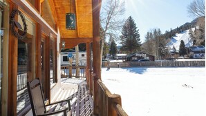 A wooden lodge with a porch, a sign reading "Alpine Lodge", and a view of a snowy landscape with a mountain in the background. - Ski View Chalet - In Town - New Property - Pet Friendly (Red River)
