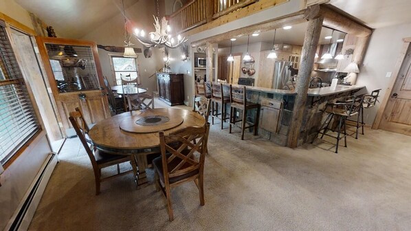 A rustic kitchen with a central island, wooden chairs, and a chandelier.