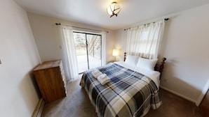 A bedroom with a bed, a nightstand, a lamp, and a window with curtains.