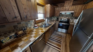 A kitchen with wooden cabinets, a tiled backsplash, stainless steel appliances, and a checkered countertop.