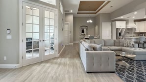 A spacious living area with a large sectional sofa, a dining table, and a kitchen in the background.