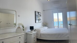 Quarto com cama, penteadeira, mesa de cabeceira, espelho e um quadro.