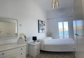 A bedroom with a bed, a dresser, a nightstand, a mirror, and a painting.