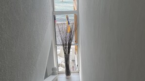 Uma escada estreita leva a uma varanda com vista para o mar e uma praia de areia.
