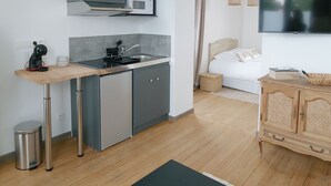 A compact living space with a kitchenette, a bed, a TV, and a small dining area.