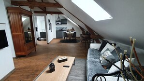 Un espace de vie de style loft comprenant un coin repas, une cuisine et un coin salon confortable avec un canapé et des coussins.