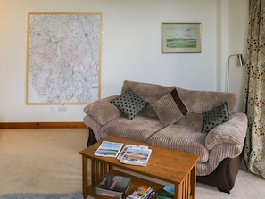 A living room with a striped sofa, a coffee table with magazines, a map on the wall, and a painting. - A lovely home from home in a superb location for exploring the town. (Penrith)