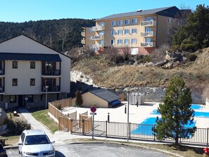 Un immeuble à plusieurs étages doté de balcons, d’une piscine et d’un espace de stationnement.