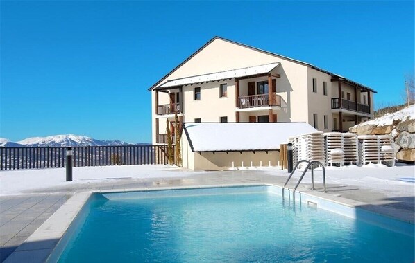 Enjoy a refreshing swim in the pool surrounded by a paved deck area with breathtaking mountain views.