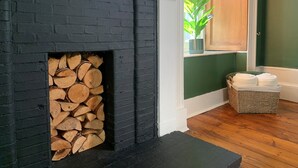 A modern living room with a black brick fireplace, a wooden floor, and a green wall. - City Centre - 1 Bed - Sleeps 2 - Pet Friendly (Aberdeen)