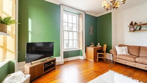 A living room with a TV, a sofa, a dining table, and a window. - City Centre - 1 Bed - Sleeps 2 - Pet Friendly (Aberdeen)
