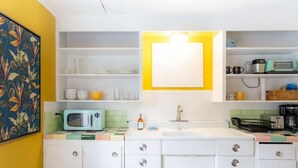 A kitchen with white cabinets, a microwave, a sink, and a yellow cabinet above the sink. - Spunky Multi-Level Unit Near Fremont Seattle (Seattle)