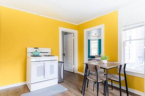 Une cuisine de taille réduite comprenant une cuisinière, un évier et une table à manger avec des chaises.