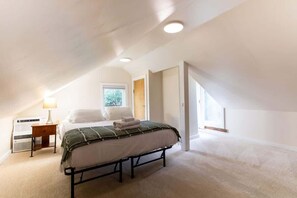 Un dormitorio con cama, mesita de noche, lámpara y ventana.