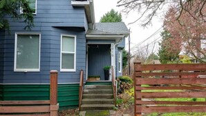 A two-story house with a front porch, a wooden gate, and a small garden area. - Spunky Multi-Level Unit Near Fremont Seattle (Seattle)