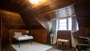 A wooden room with a bed, a small table, a chair, and a window with curtains. - Spunky Multi-Level Unit Near Fremont Seattle (Seattle)