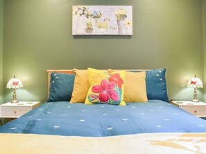 A bed with floral pillows, a blue bedspread, and a painting above. - 1 bedroom accommodation in Wingerworth (Wingerworth)