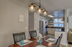 Enjoy meals in the kitchen with a central island, stainless steel appliances, and a dining area with a wooden table and pendant lights.