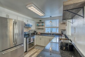 Una cocina moderna con electrodomésticos de acero inoxidable, una isla central y un amplio ventanal que proporciona luz natural.