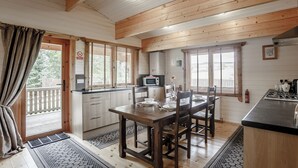 Un interior de madera con una mesa de comedor, sillas, una zona de cocina y un balcón.