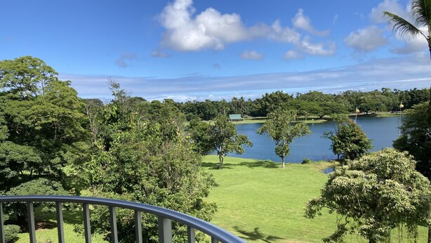 Une vue depuis un balcon donnant sur un lac, entouré d’une végétation luxuriante et d’arbres.