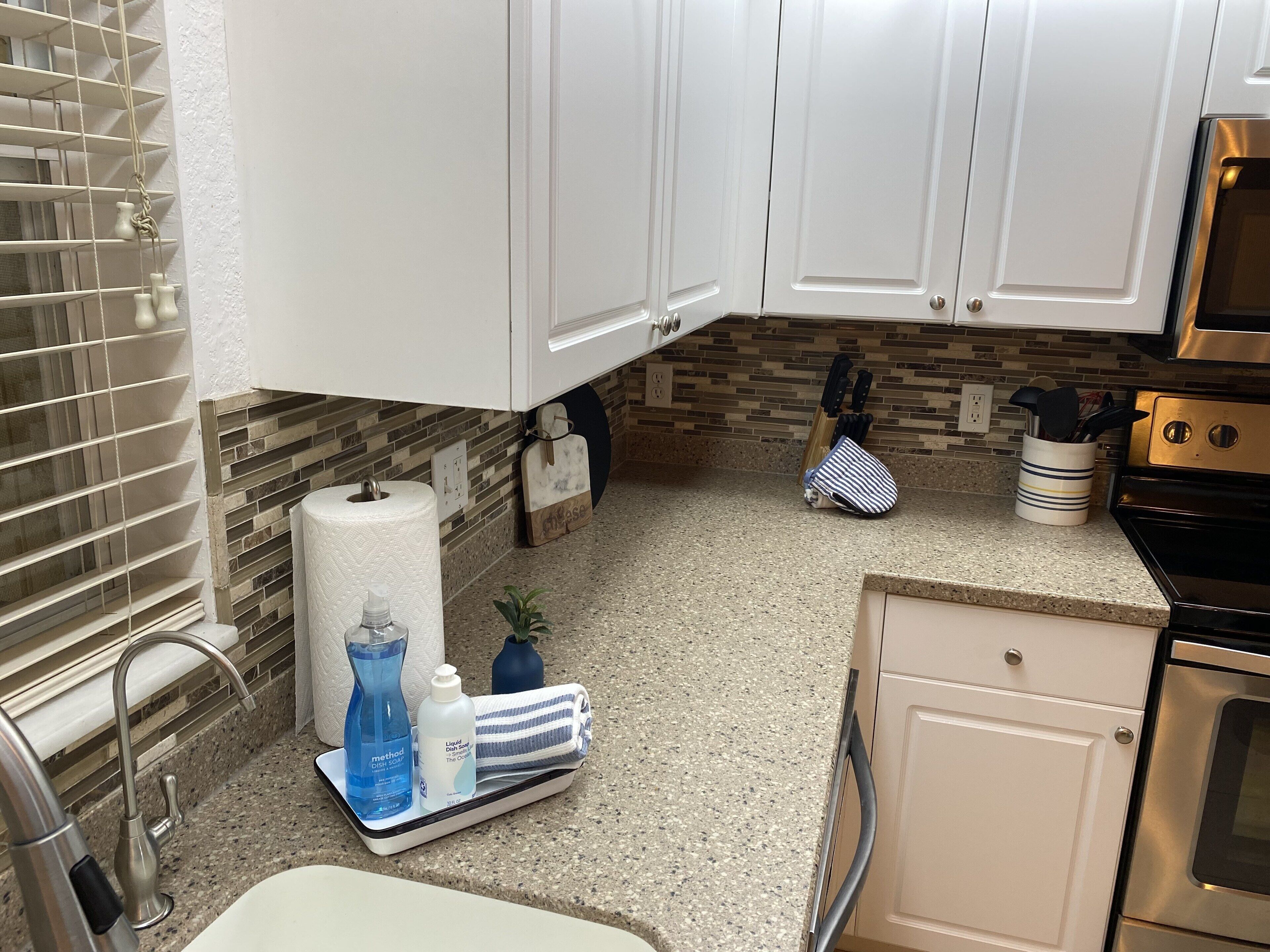 A kitchen with white cabinets, a granite countertop, a stainless steel oven, and a built-in dishwasher.