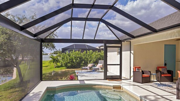 A covered outdoor swimming pool with a view of a backyard and a house. - Oasis home in SW Florida - Heated in-ground pool on a fresh water canal! (Cape Coral)