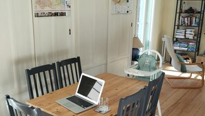 A dining area with a wooden table, four chairs, a laptop, and a glass. - 3-bedroom apartment in the heart of a medieval village in Vallespir (Pyrenees). (Arles sur Tech)