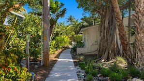 A pathway leading through a garden with various plants and trees. - Stunning Views Casual Lux Décor - Directly on the Beach Jensen's “On the Gulf” North Beach 2 (Captiva)