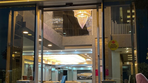 Eine Hotelhalle mit Glastür, einer Kronleuchter, einem Empfangsbereich und einer Sitzecke.