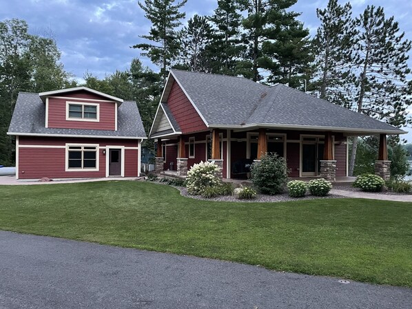 A two-story house with a red exterior, a covered porch, and a well-maintained lawn. - Modern Lake House with Stunning Views (Medford)
