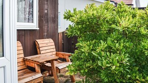 Puinen penkki ja pöytä ovat sijoitettu rakennuksen eteen, ja rakennuksessa on kyltti, jossa lukee ”20 SIXTH AVE”.