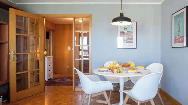 Un coin repas avec une table ronde, des chaises blanches et un luminaire suspendu.