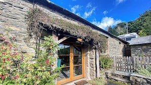 A stone building with a wooden door and a small porch. - 2 bedroom accommodation in Satterthwaite, near Coniston (Satterthwaite, near Coniston)