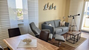 Una sala moderna con un sofá gris, una mesa de comedor de madera y un telescopio.