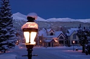 Ein schneebedecktes Dorf mit traditionellen Häusern und einer markanten Straßenlaterne im Vordergrund.