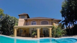 Uma casa grande com piscina em frente.