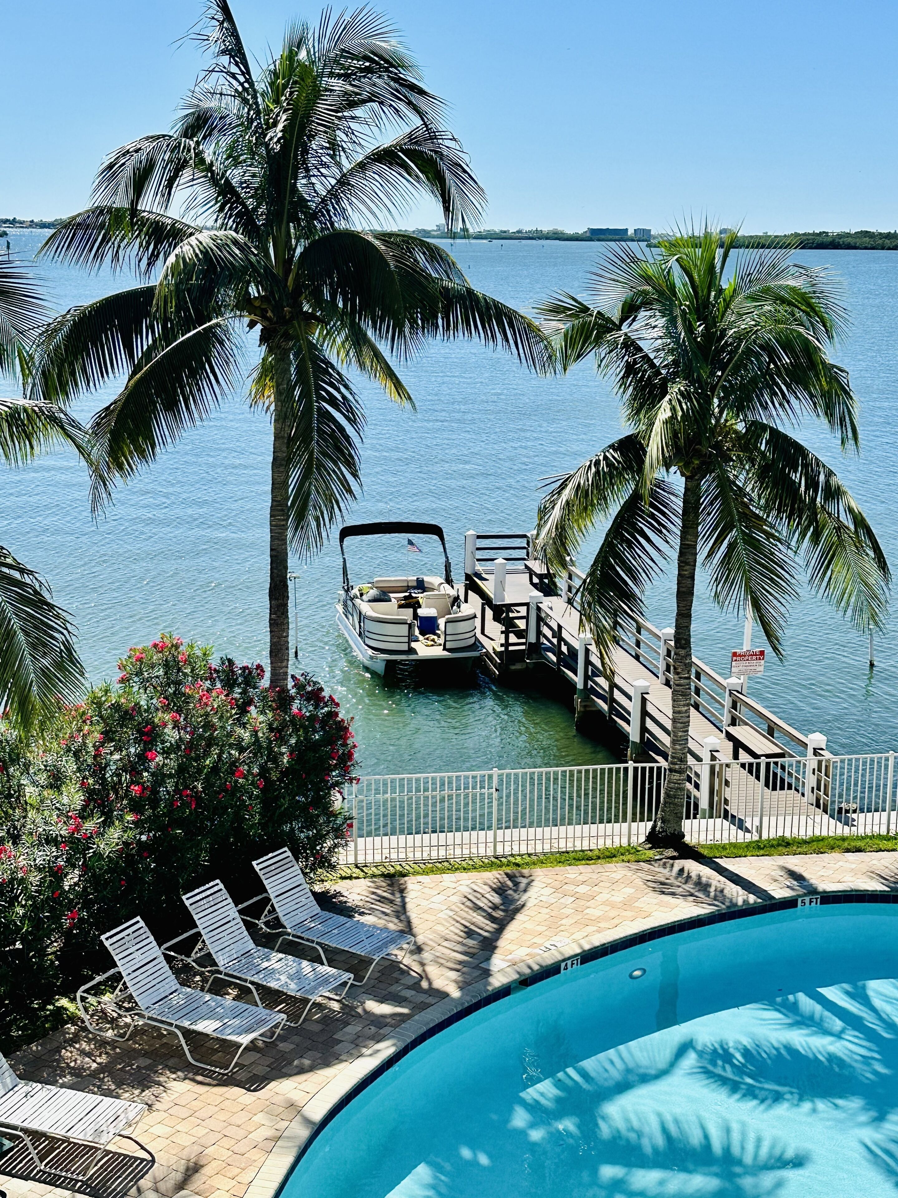 A private dock with a boat, a swimming pool, and lounge chairs.